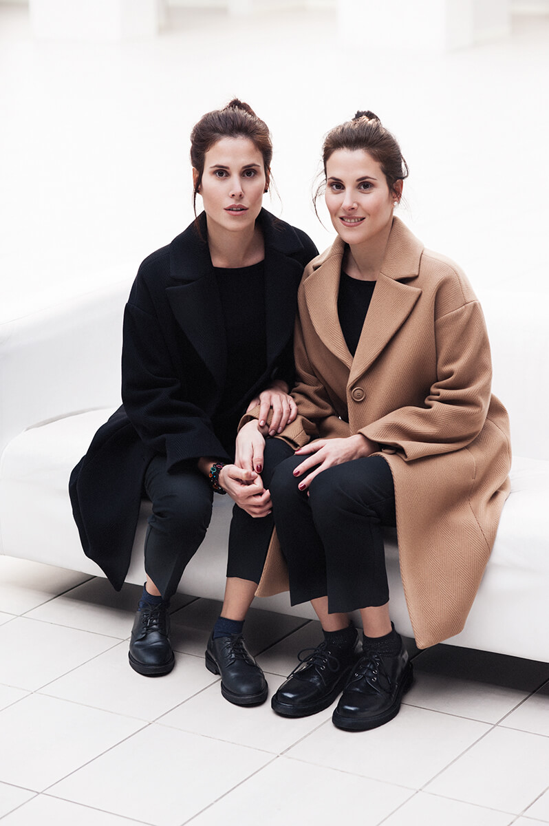 twin sisters wearing black and brown winter coats