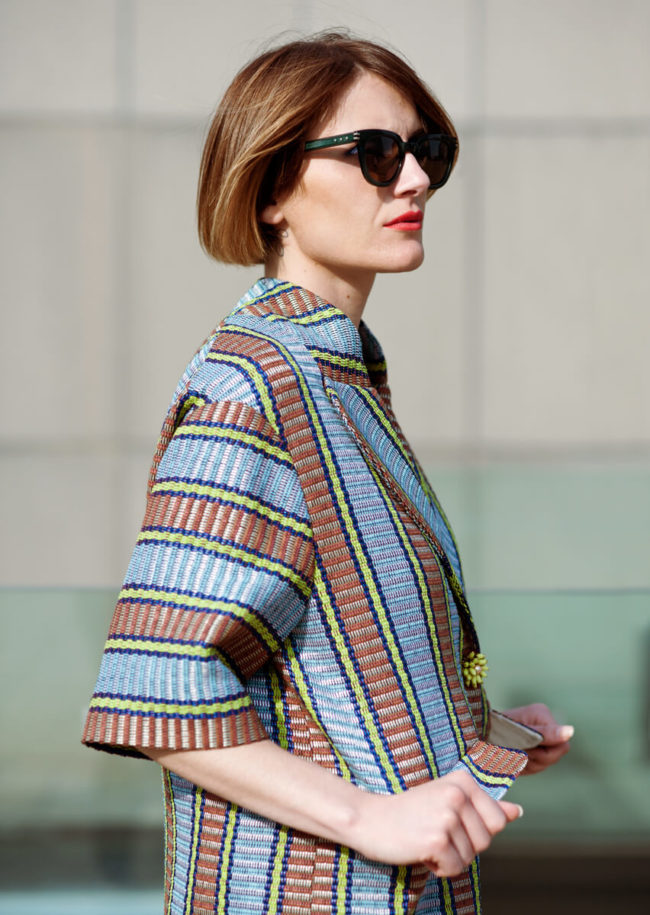model with red lips wearing a colorful striped jacket