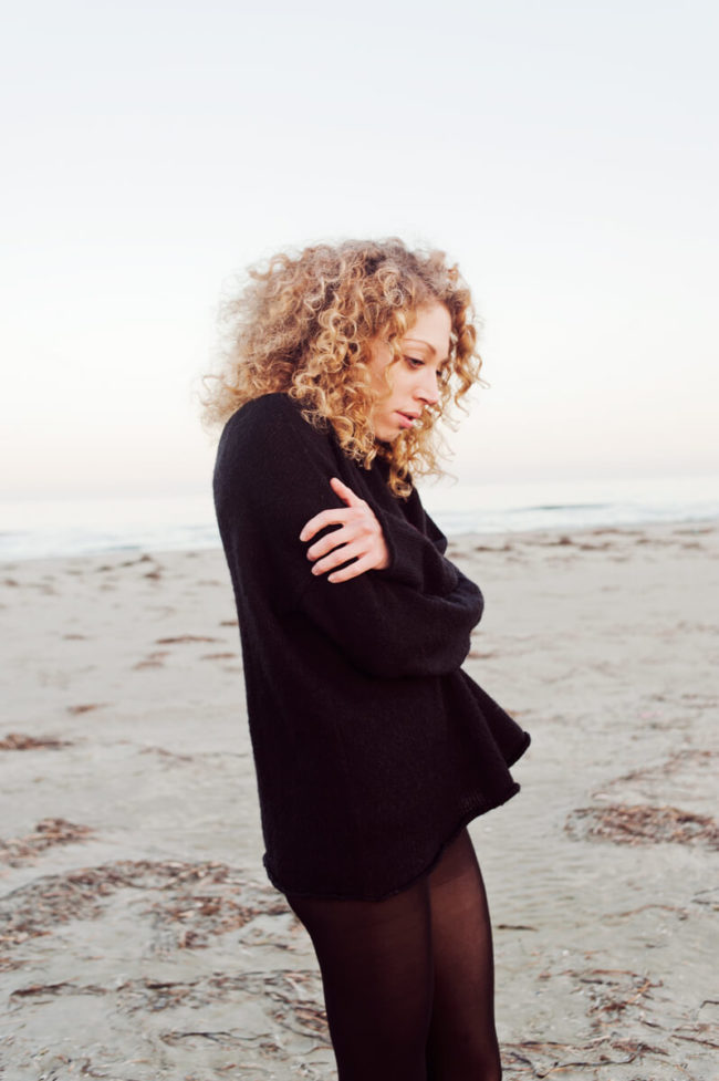 young girl on the beach half naked and with curly blond hair