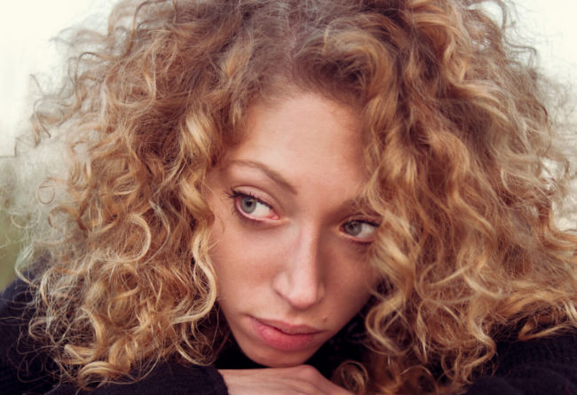 young girl with curly blond hair and melancholy look
